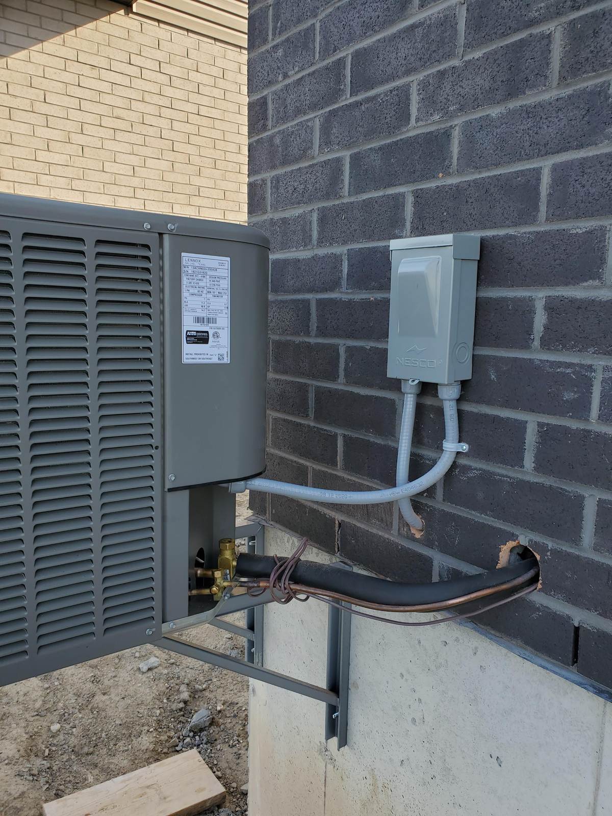 AC disconnect box mounted beside an outdoor condenser by Archvolt Electric